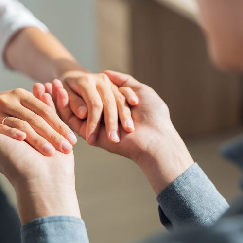 Close-up of hands of young man holding hands of woman. Man proposing to his girlfriend indoors